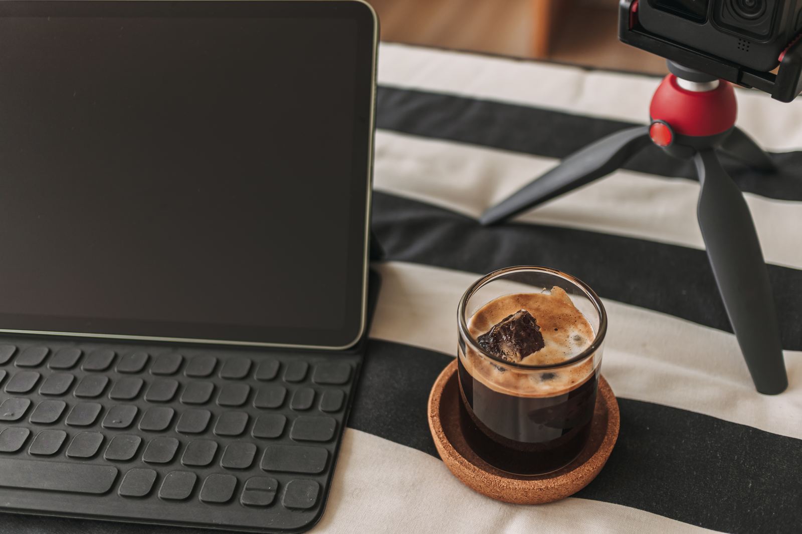 Coffee on content creator desk with tripod camera and laptop