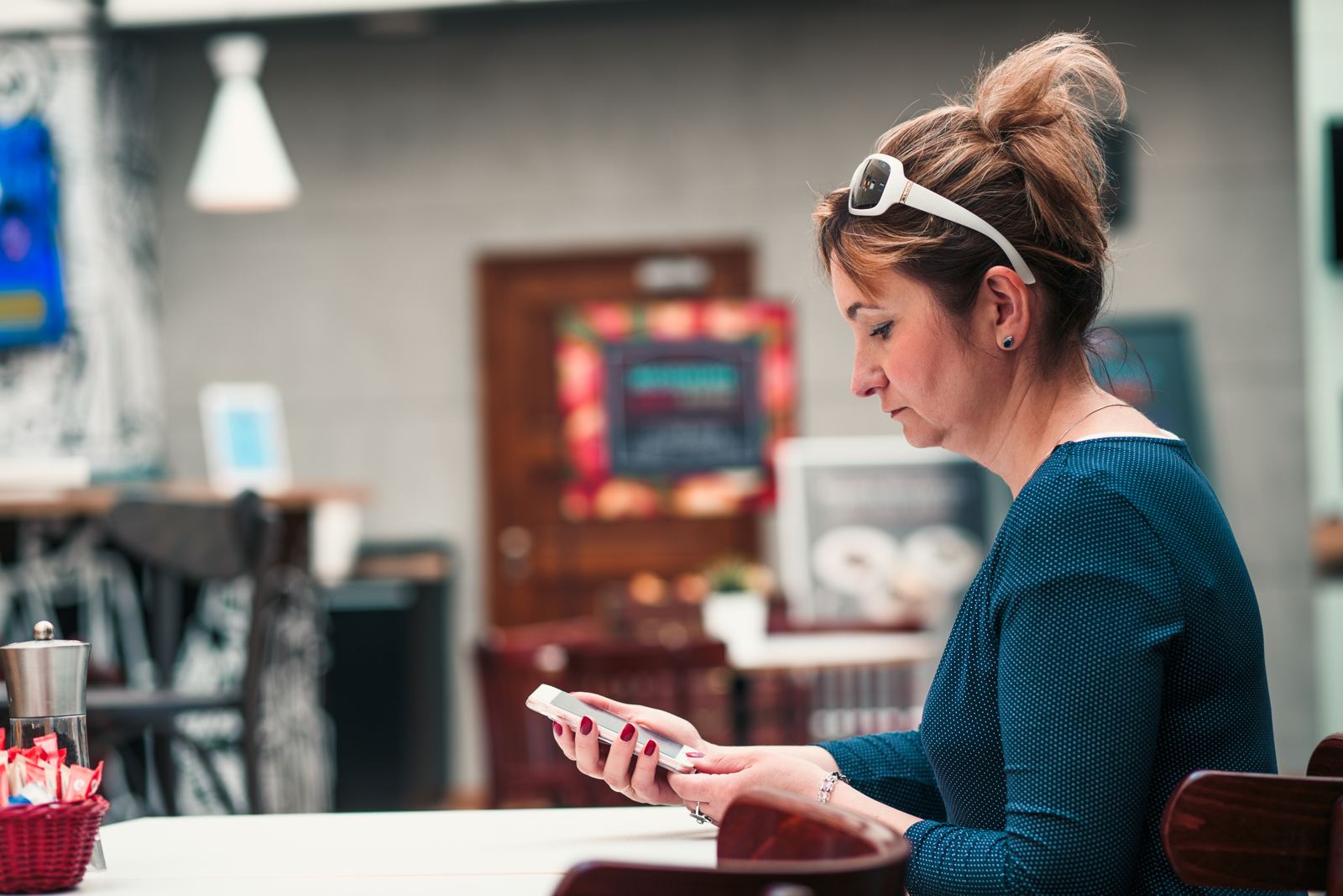 Woman using mobile phone while sitting at table in restaurant