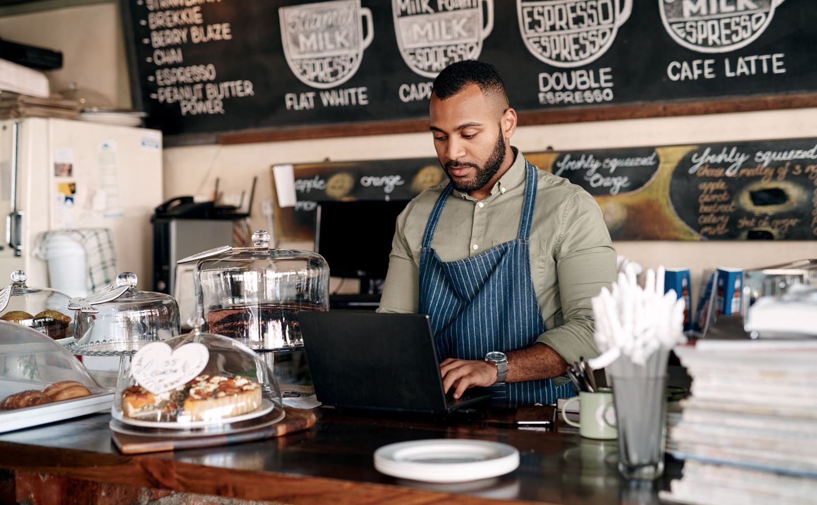 Typing laptop and man at counter in coffee shop for online order inventory and stock for small business Cafe