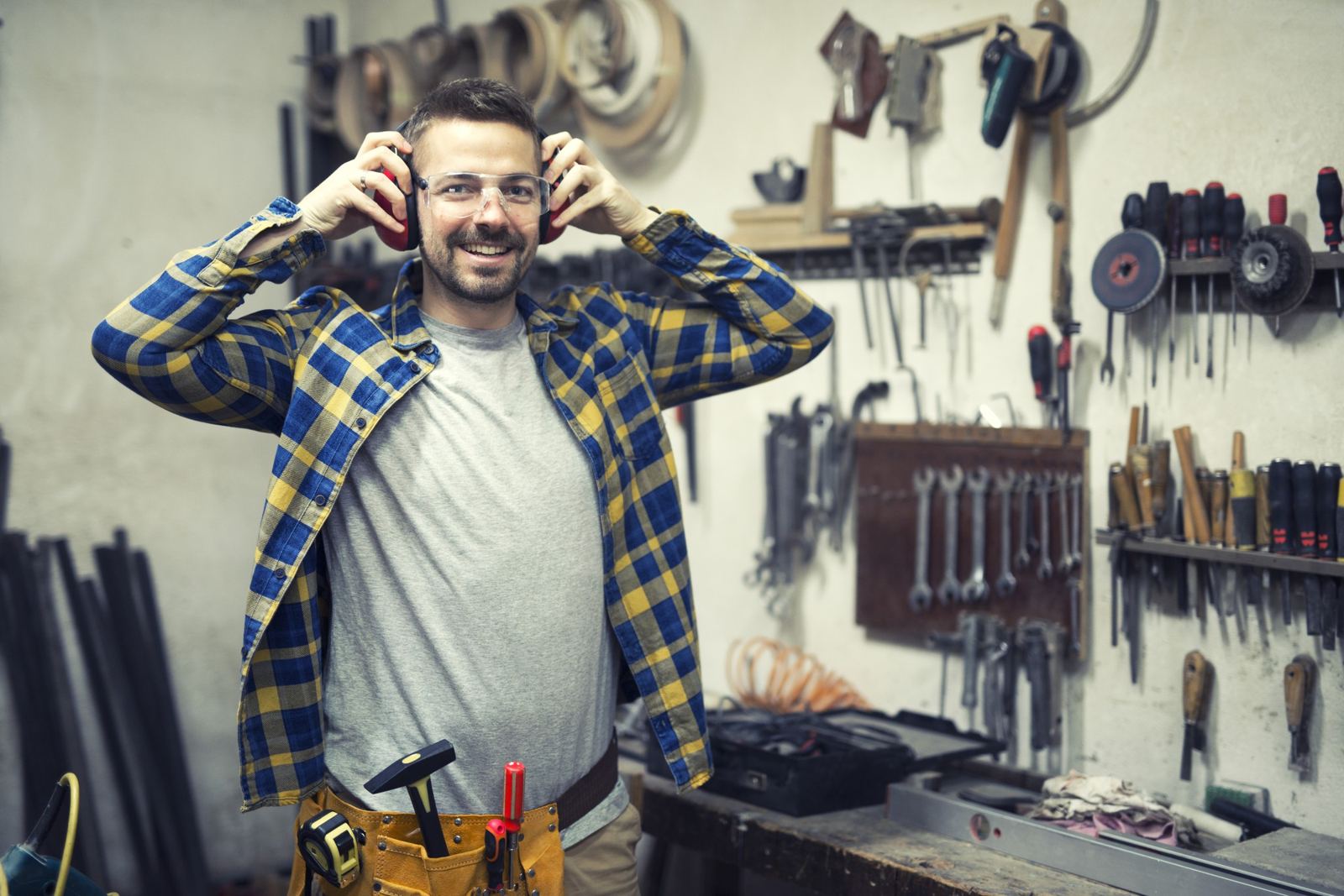 Carpenter in workshop putting on ears protection and getting ready for work