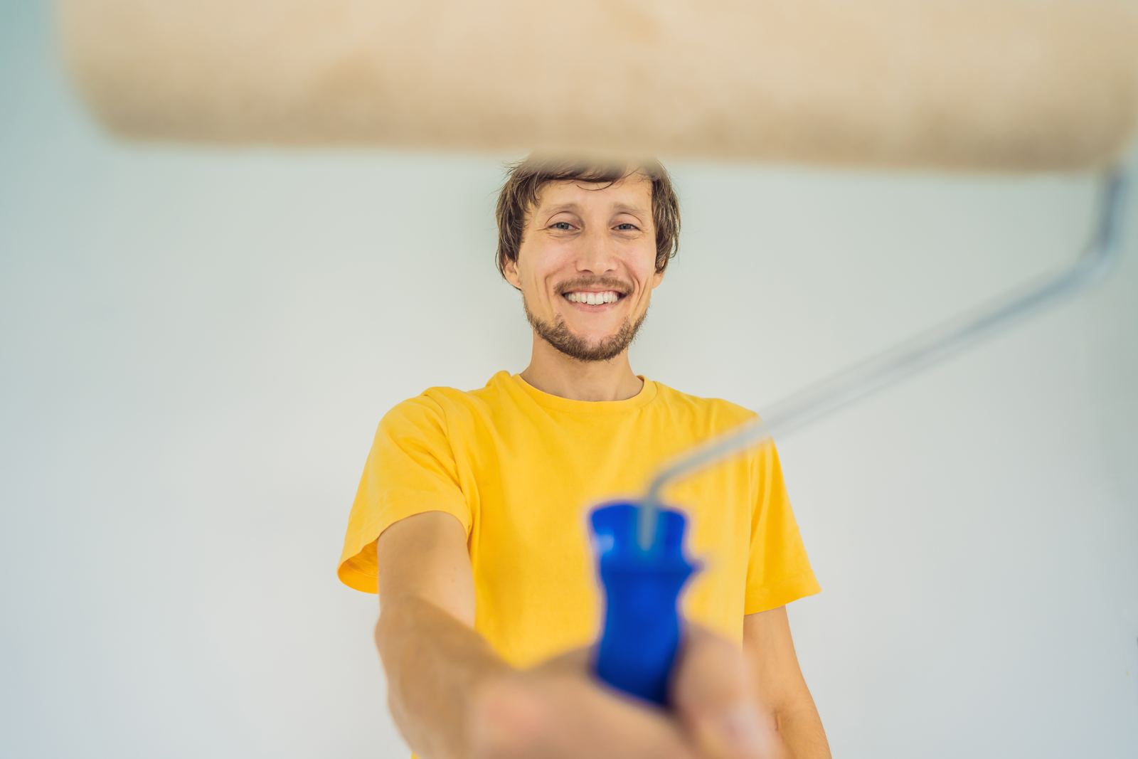 One male house painter worker painting and priming wall with painting roller DIY